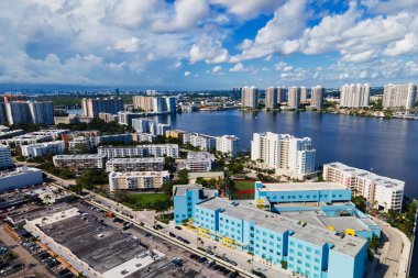 Kumsal boyunca renkli binalar dik duruyor. Palmiye ağaçları ve dalgalar sahneyi tamamlıyor.