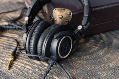 Klasik ahşap masa üzerinde altın kriko bulunan profesyonel siyah kulaklıklar.