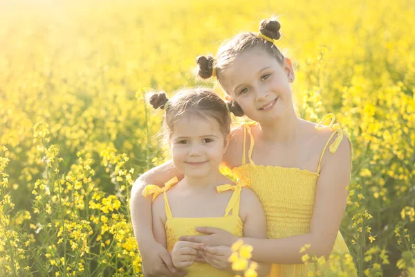 Meninas felizes no campo de sementes de colza — Fotografia de Stock