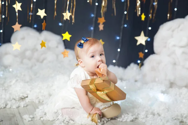 Linda niña con un regalo en un estudio con una decoración de estrellas de oro —  Fotos de Stock