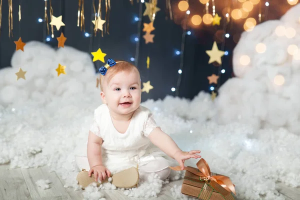 Menina bonito com um presente em um estúdio com uma decoração estrelas de ouro — Fotografia de Stock