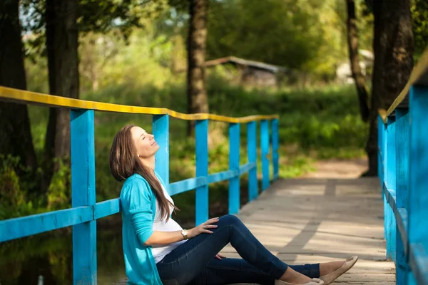 Retrato de una joven embarazada feliz en un puente azul de madera . — Foto de Stock