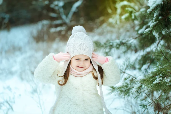 Маленька дівчинка в білій шубці в зимовому лісі — стокове фото