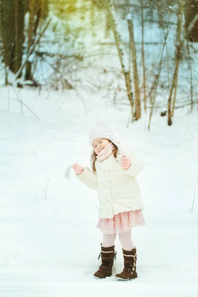 Маленькая девочка в белом шубе в зимнем лесу — стоковое фото