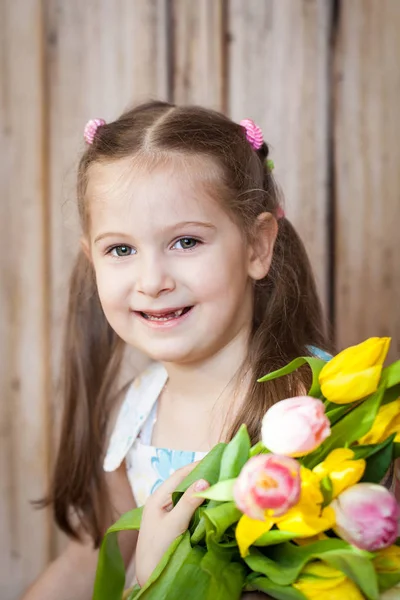 Little cute girl holding bouquet of tulips