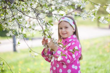 Çiçek açan kiraz ağacının bahçesinde tatlı bir kız.