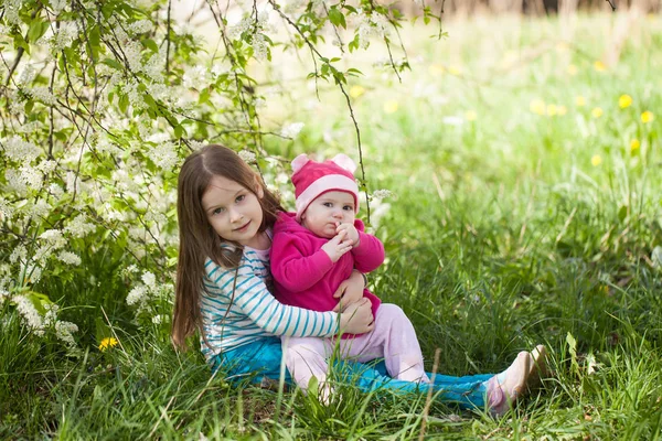 Ragazze sveglie in un giardino fiorito albero ciliegio uccello — Foto Stock