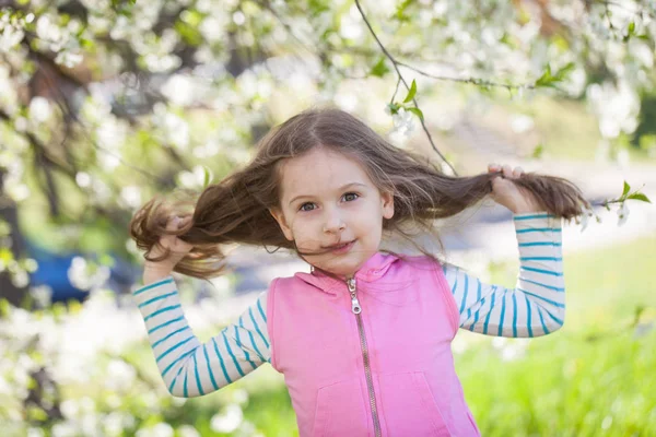 Niña linda en un floreciente jardín de cerezos. —  Fotos de Stock