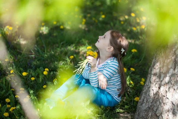 Nettes Mädchen auf einer Lichtung von Löwenzahn — Stockfoto