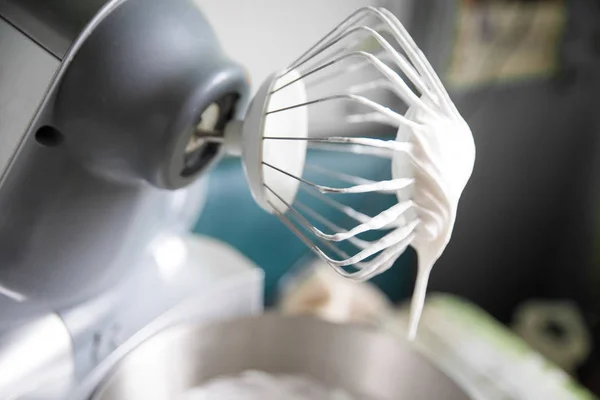 Woman whipping cream using electric hand mixer on the gray rustic wooden  table Stock Photo