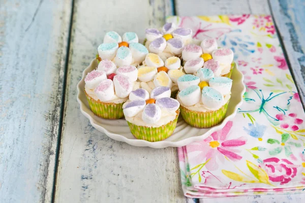 Cupcakes decorated with butter cream and marshmallow flowers — Stock Photo, Image