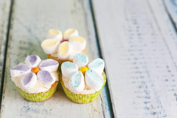 Cupcakes decorated with butter cream and marshmallow flowers — Stock Photo, Image