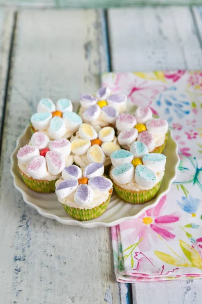 Cupcakes decorated with butter cream and marshmallow flowers — Stock Photo, Image