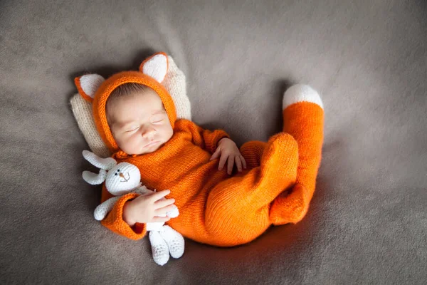 Örgü tavşan oyuncağıyla şirin tilki kostümü içinde uyuyan yeni doğmuş bebek. Cadılar Bayramında Şükran Günü kartı.