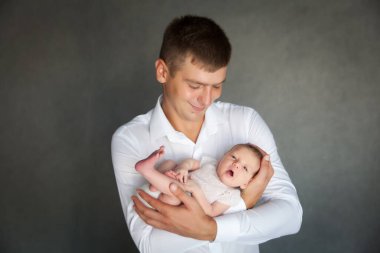 Baba yeni doğmuş bebeği taşıyor. Küçük kızı olan genç bir adamın portresi. 3 haftalık bebek, babasının ellerinde. Sağlıklı ve mutlu çocukluk kavramı