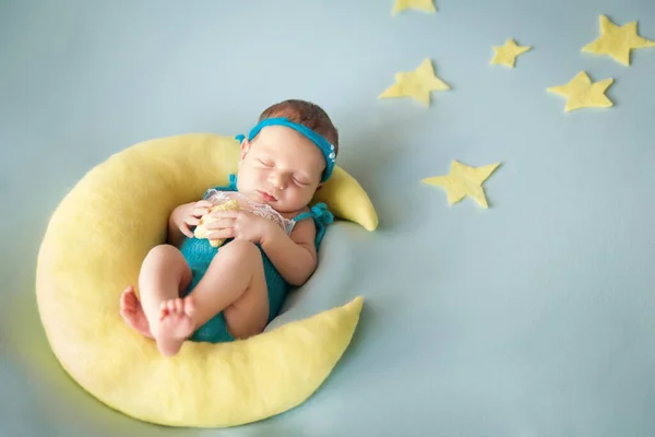 Ellerinde örgü yıldız oyuncağıyla ay yastığında uyuyan yeni doğmuş tatlı bir kız bebek. Sağlıklı çocuk, çocuk bakımı ve mutlu annelik kavramı, mutlu doğum.