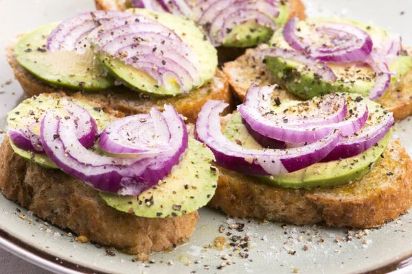 Sandwich mit frischer Avocado und Zwiebeln auf einem Teller — Stockfoto