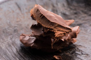 Koyu arkaplana saçılmış kırık acı ya da süt çikolata yığını.