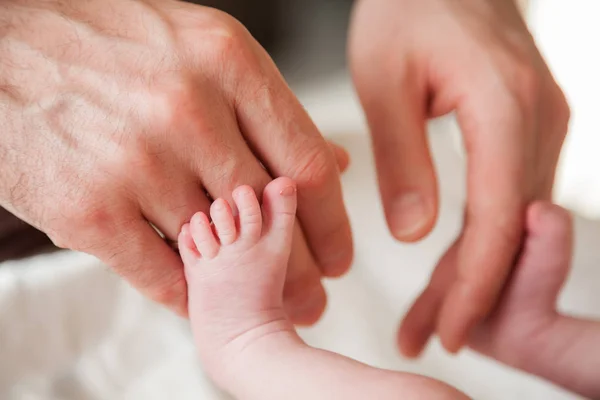 生まれたばかりの赤ちゃんの足に触れる父の手 — ストック写真