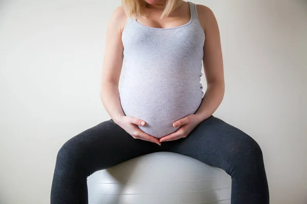 无法辨认的孕妇坐在一个适合球举行她的肚子 — 图库照片