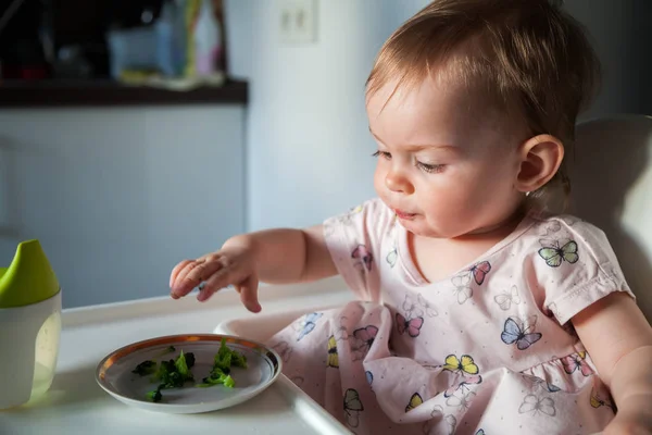 ブロッコリーの小さな断片を食べるかわいい女の子 — ストック写真