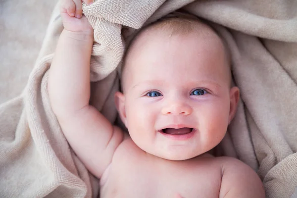 一个可爱的微笑的女婴躺在米色毛巾的肖像 — 图库照片