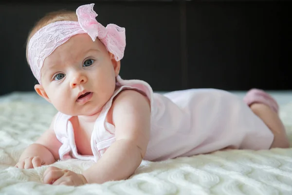 可爱的女婴与粉红色的弓和礼服 躺在肚子上 — 图库照片