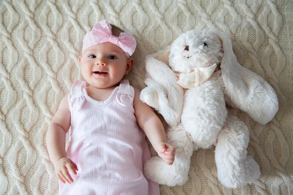 可爱的女婴在粉红色的礼服躺在白色兔子玩具附近 — 图库照片