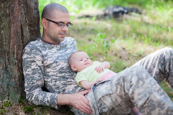 Pai em uniforme de camuflagem e seu bebê — Fotografia de Stock