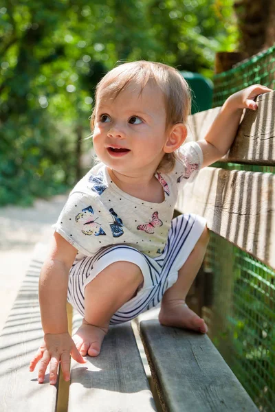 Baby girl sitting on her haunches on a bench — Stock Photo, Image