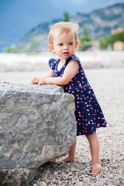 Baby meisje staande in de buurt van de grote steen — Stockfoto