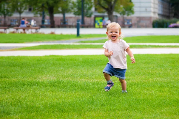 Laughing baby girl running on the green grass — Stock Photo, Image