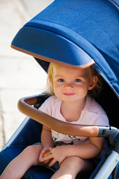 Glimlachend meisje zittend in een kinderwagen — Stockfoto