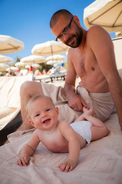 Bebê deitado na praia com seu pai — Fotografia de Stock