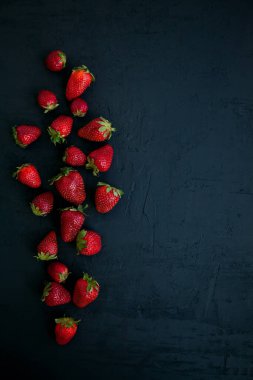 Siyah zemin üzerinde taze kırmızı çilekler, üst görünüm, kopyalama alanı