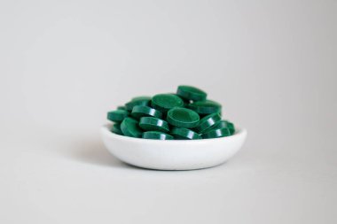 Gri arka planda yakın plan spirulina hapları yığını. Süper yemek konsepti. β ulina diyet takviyesi