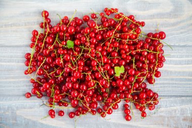 Kırsal ahşap arka planda sulu taze kırmızı frenk üzümü yığını.