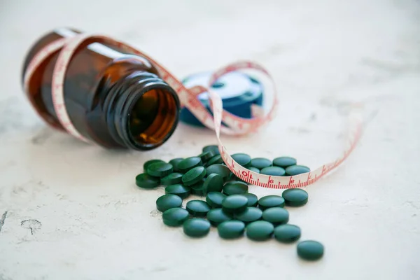 Garrafa Close Pílulas Espirulina Verde Com Uma Fita Métrica Fundo — Fotografia de Stock
