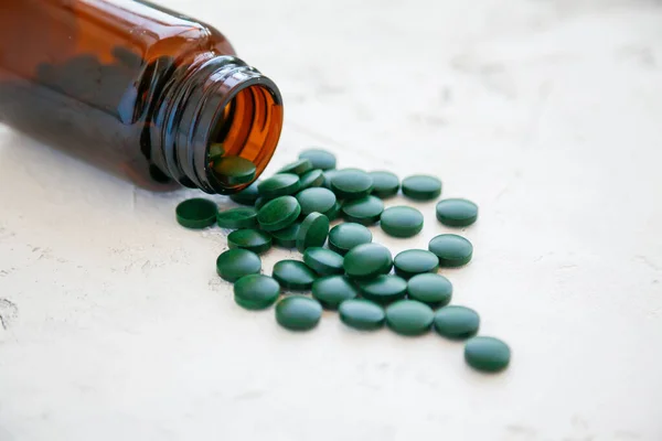 Close Green Spirulina Pills Dropped Out Bottle White Concrete Background — Stock Photo, Image