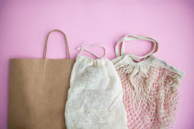 Pembe arka planda tekstil ve kağıt eko torbaları. Çevre dostu, yeniden kullanım ve sıfır atık konsepti. Üst manzara, düz uzanma