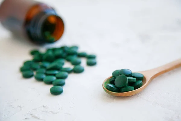 Close Green Spirulina Pills Dropped Out Bottle White Concrete Background — Stock Photo, Image