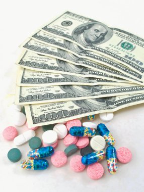 Beyaz arka planda bir sürü hap ve dolar var.