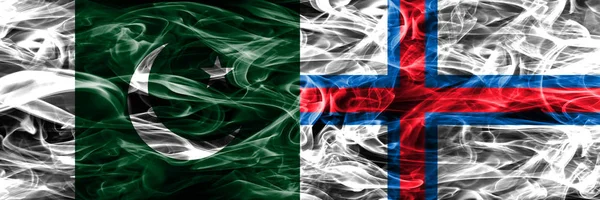 Pakistan vs Faroe Islands smoke flags placed side by side. Thick colored silky smoke flags of Pakistan and Faroe Islands