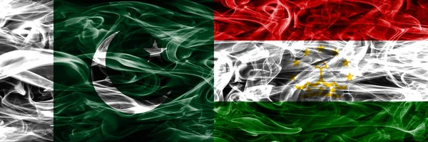 Pakistan vs Tajikistan smoke flags placed side by side. Thick colored silky smoke flags of Pakistan and Tajikistan