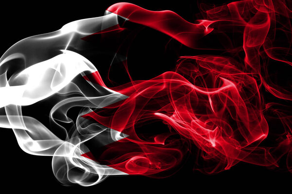 National flag of Bahrain made from colored smoke isolated on black background. Abstract silky wave background.
