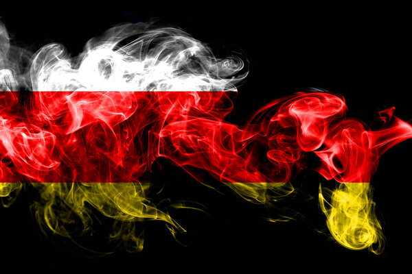 National flag of South Ossetia made from colored smoke isolated on black background. Abstract silky wave background.