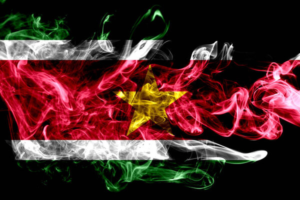 National flag of Suriname made from colored smoke isolated on black background. Abstract silky wave background.