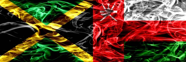 Jamaika vs Umman Umman bayrakları yan yana yerleştirilmiş duman. Kalın ipeksi duman bayrakları, Jamaika ve Umman Umman renkli