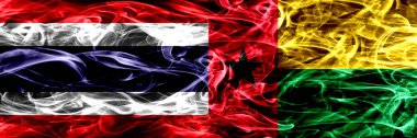 Tayland vs Gine Bissau bayrakları yan yana yerleştirilmiş duman. İpeksi duman bayrakları renkli kalın soyut