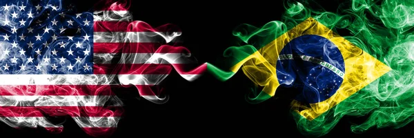 Estados Unidos da América vs Brasil, bandeiras místicas fumegantes brasileiras colocadas lado a lado. Bandeiras de fumo sedoso de cor grossa da América e do Brasil, Brasileiro — Fotografia de Stock